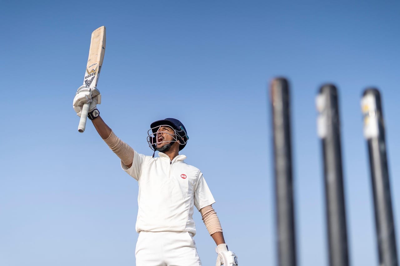 A Professional Cricket Player Holding a Bat in the Air